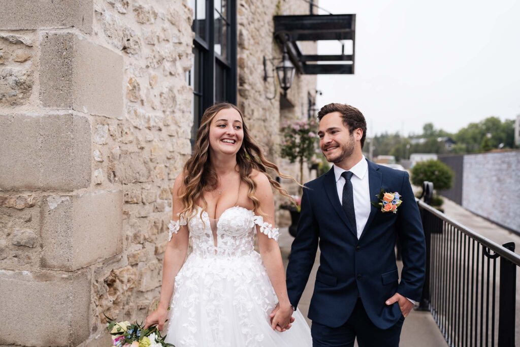 Bride and Groom holding hands and smiling in Elora, ON